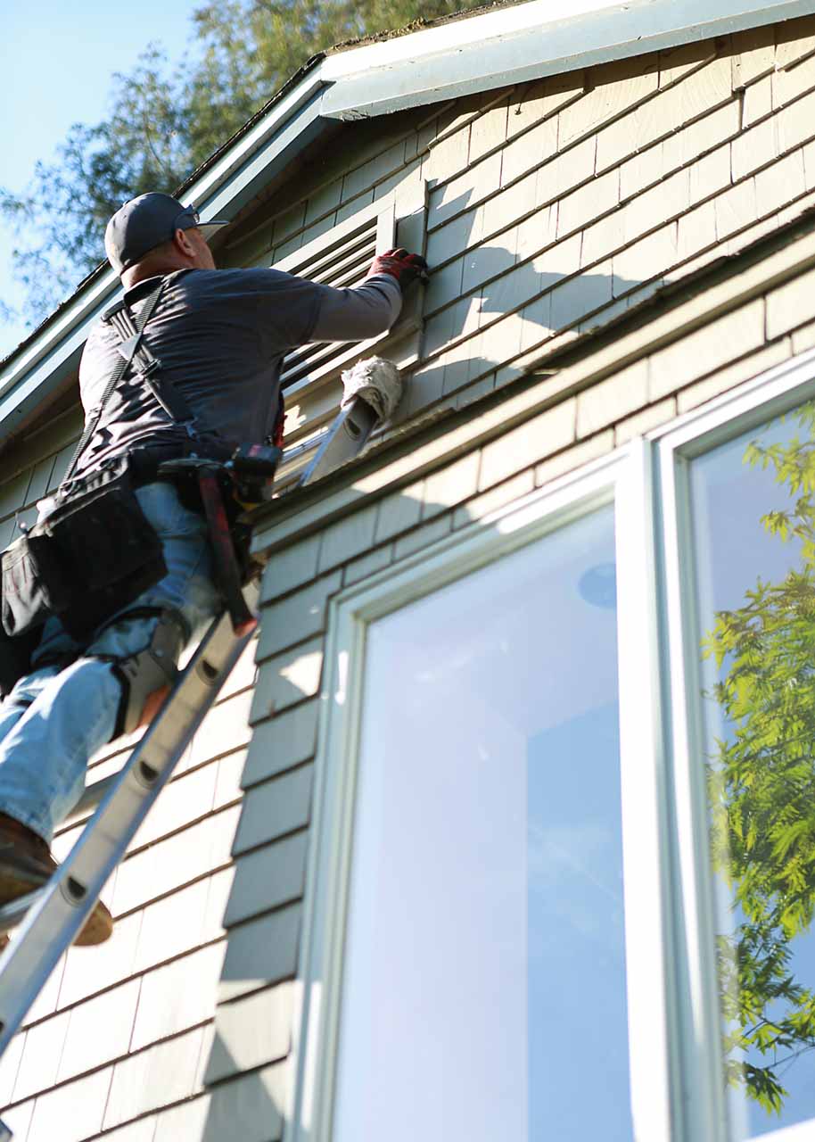 contractor installing fire ember safe gable vent on ladder